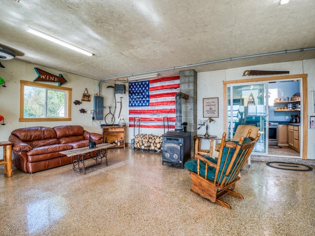 living area with a wood stove, speckle patterned floor, and electric panel