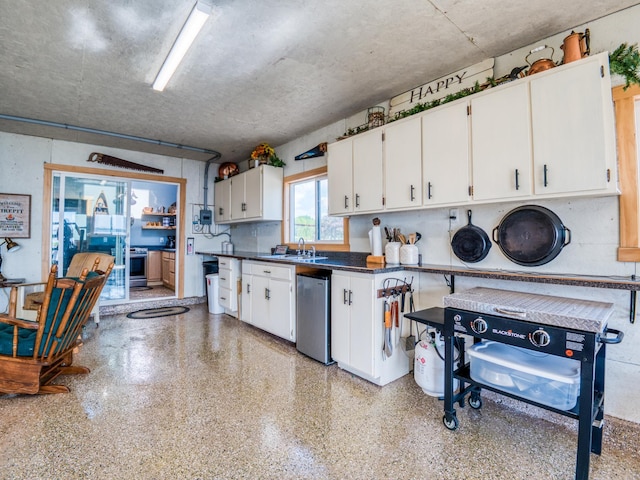 kitchen with a sink, white cabinetry, dark countertops, refrigerator, and dark speckled floor