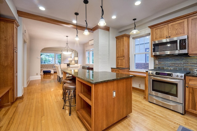 4448 Aldrich Ave S, Minneapolis, MN 55419 - kitchen with stainless steel appliances, a center island, brown cabinets, tasteful backsplash, and arched walkways