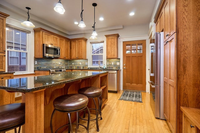4448 Aldrich Ave S, Minneapolis, MN 55419 - kitchen featuring stainless steel appliances, decorative backsplash, brown cabinetry, light wood-type flooring, and a kitchen bar