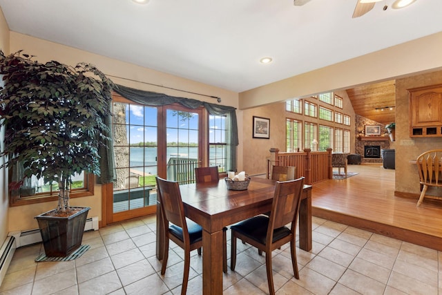 1823 313th Ave NE, Isanti Twp, MN 55008 - dining area featuring lofted ceiling, light tile patterned floors, a water view, a ceiling fan, and a stone fireplace