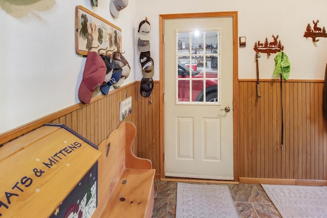 doorway with a wainscoted wall and wooden walls