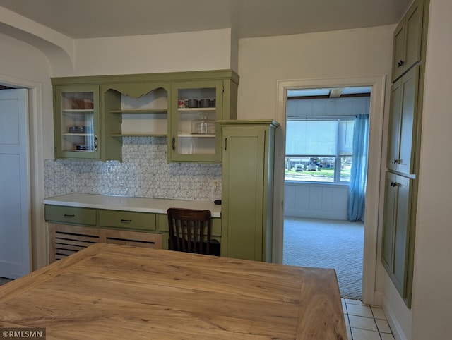 532 Main St S, Sauk Centre, MN 56378 - kitchen featuring green cabinetry, light carpet, backsplash, light tile patterned floors, and glass insert cabinets