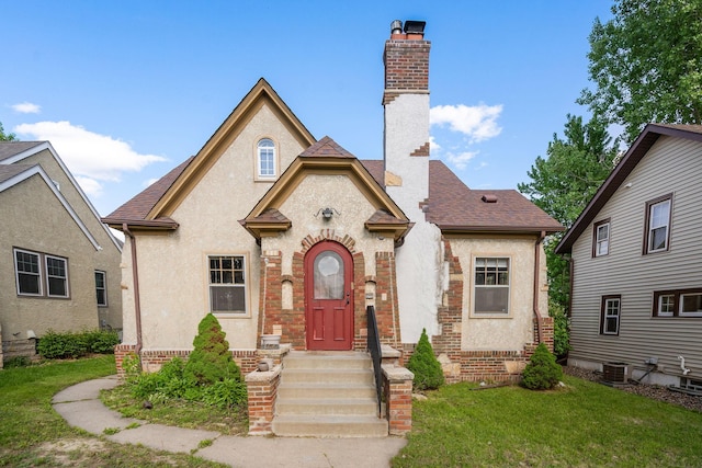 3330 Irving Ave N, Minneapolis, MN 55412 - view of front of house featuring a chimney, a front lawn, stucco siding, a shingled roof, and central air condition unit