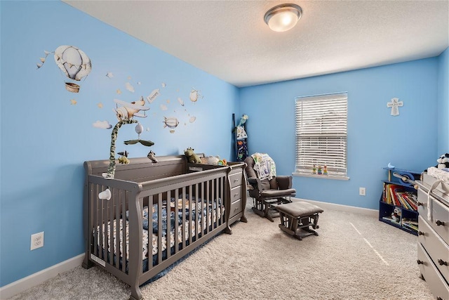 bedroom with carpet, baseboards, a crib, and a textured ceiling