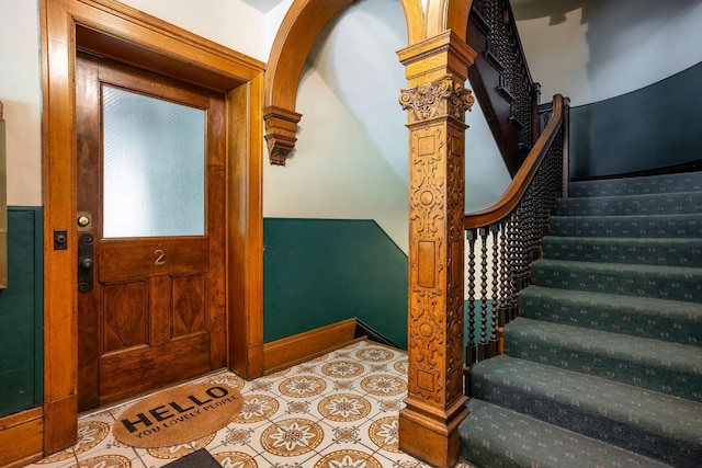 foyer entrance with stairway, tile patterned floors, and decorative columns