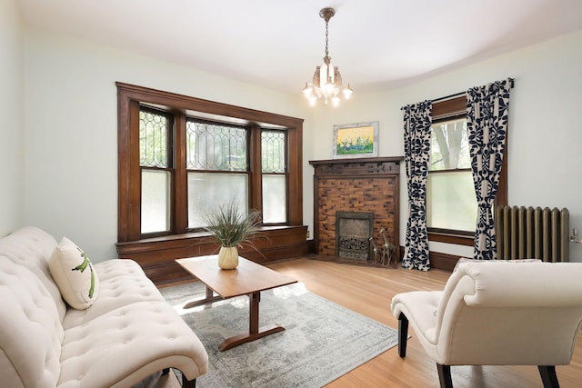 living room featuring radiator, a chandelier, wood finished floors, and a fireplace