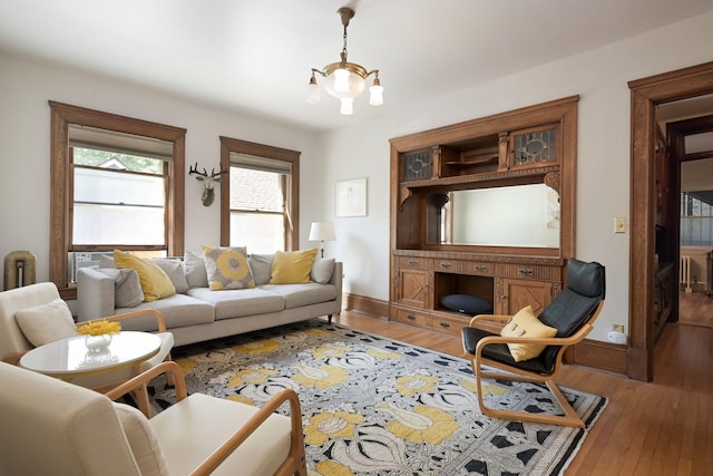 living room featuring hardwood / wood-style floors, a chandelier, and baseboards
