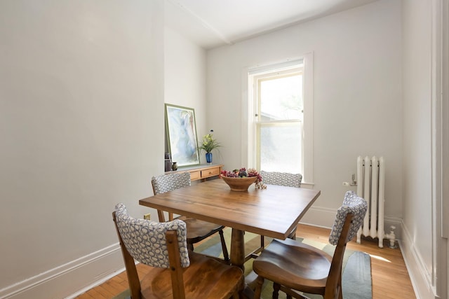 dining space featuring radiator, light wood-type flooring, and baseboards