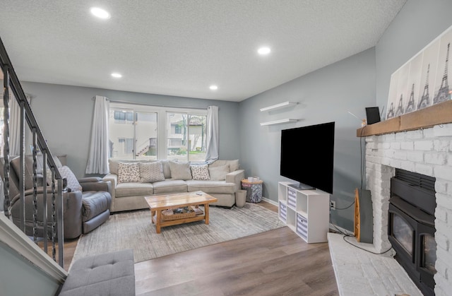 living area featuring wood finished floors, recessed lighting, a textured ceiling, and a brick fireplace