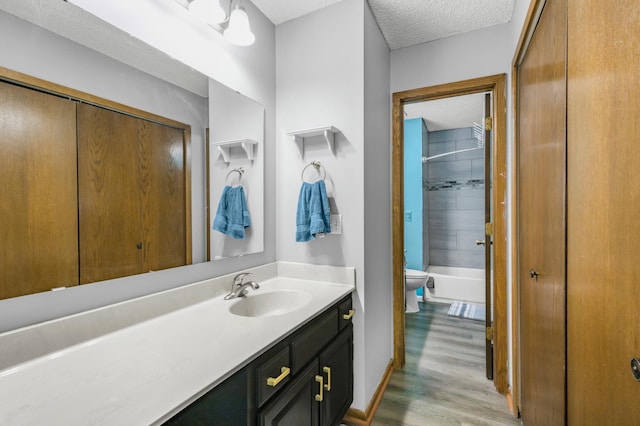 full bathroom with a textured ceiling, wood finished floors, toilet, vanity, and baseboards