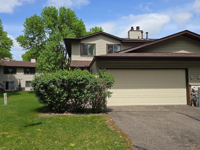 view of front of home featuring a front lawn, a chimney, asphalt driveway, roof with shingles, and a garage
