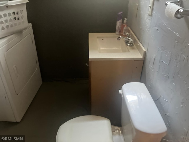 half bathroom with washer / dryer, vanity, and toilet