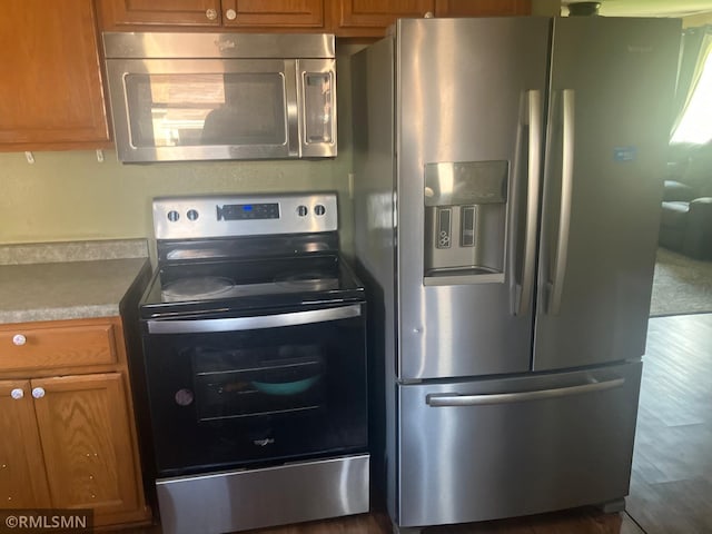 kitchen featuring stainless steel appliances, dark wood finished floors, and brown cabinetry