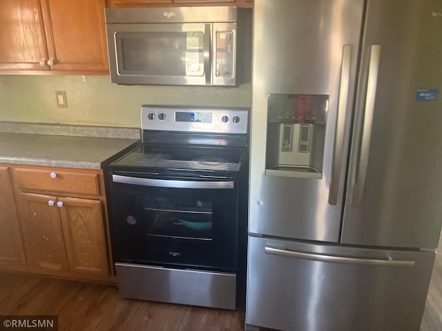 kitchen with appliances with stainless steel finishes, dark wood-style floors, and brown cabinetry