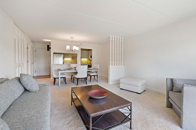living room with a chandelier, light colored carpet, and baseboards