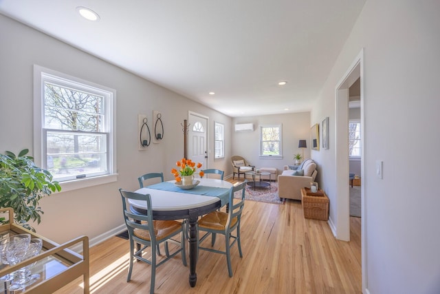 dining room featuring a wall unit AC, light wood finished floors, baseboards, and recessed lighting