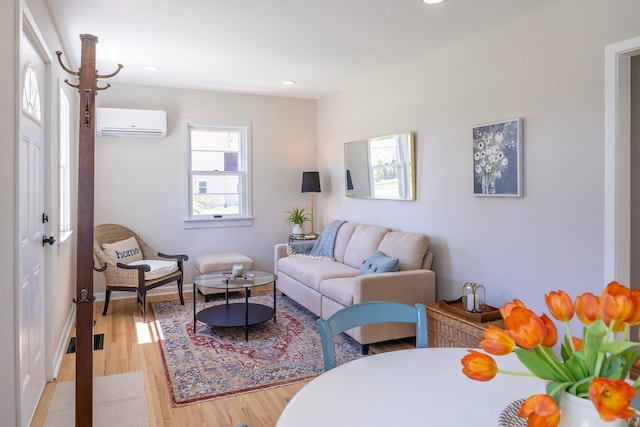 living room with a wall mounted AC, light wood finished floors, recessed lighting, and baseboards