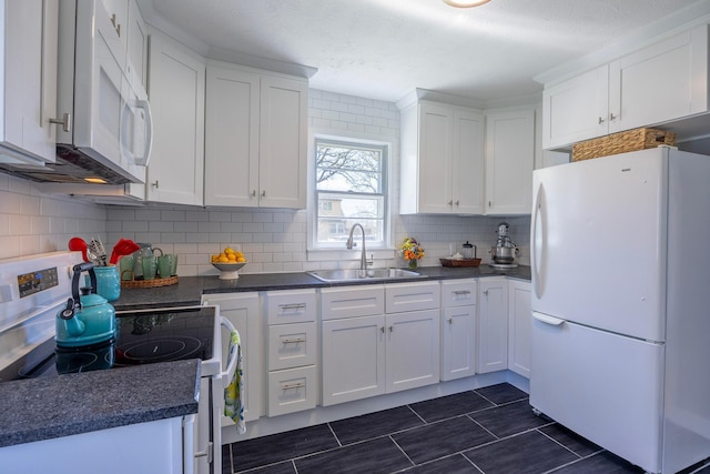 kitchen with white appliances, a sink, dark countertops, white cabinetry, and a textured ceiling