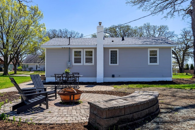 rear view of property featuring a fire pit, a patio, and a chimney