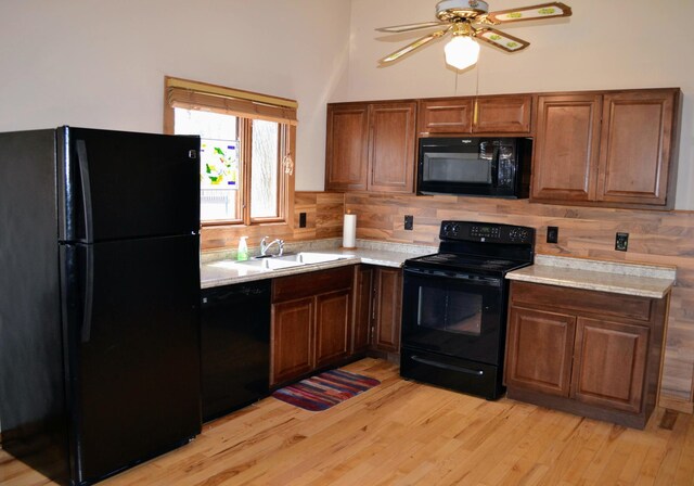 109 Eagle Lake Dr, Maple Grove, MN 55369 - kitchen featuring black appliances, a sink, light countertops, light wood-type flooring, and a towering ceiling