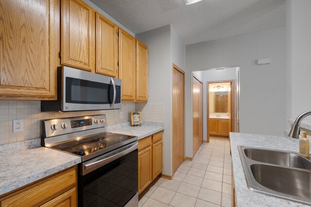 8497 Cortland Rd, Eden Prairie, MN 55344 - kitchen with appliances with stainless steel finishes, a sink, light countertops, decorative backsplash, and light tile patterned floors