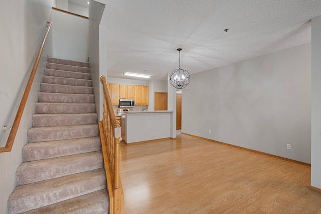 8497 Cortland Rd, Eden Prairie, MN 55344 - staircase with wood finished floors, a chandelier, baseboards, and a textured ceiling