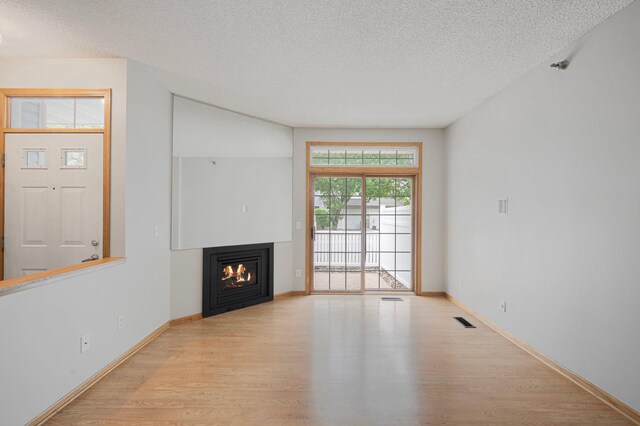 8497 Cortland Rd, Eden Prairie, MN 55344 - unfurnished living room with a textured ceiling, wood finished floors, a glass covered fireplace, and baseboards