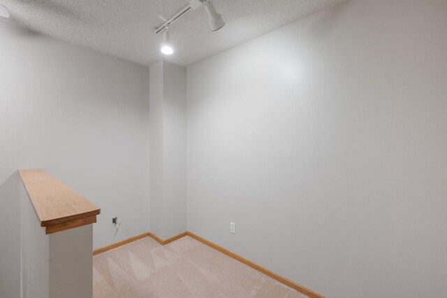 8497 Cortland Rd, Eden Prairie, MN 55344 - spare room with baseboards, a textured ceiling, light carpet, and track lighting