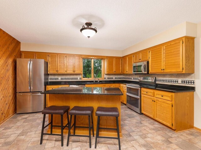 71156 Csah 18, Collinwood Twp, MN 55325 - kitchen with stainless steel appliances, backsplash, stone tile floors, wood walls, and a kitchen bar