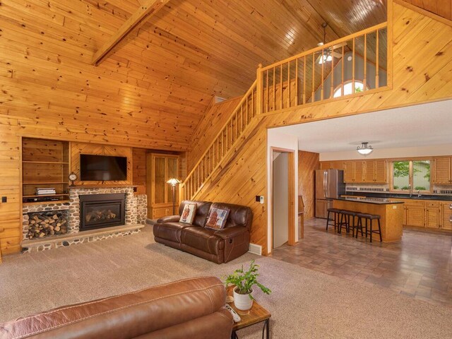 71156 Csah 18, Collinwood Twp, MN 55325 - carpeted living area with high vaulted ceiling, wooden walls, a sink, a stone fireplace, and stairway
