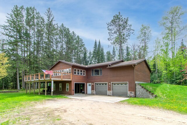 51850 Scenic Hwy Unit 7, Bigfork, MN 56628 - view of front of property with dirt driveway, a garage, stone siding, a wooden deck, and a front lawn