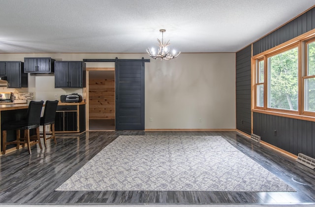 51850 Scenic Hwy Unit 7, Bigfork, MN 56628 - kitchen with a barn door, baseboards, a chandelier, dark wood-type flooring, and a textured ceiling