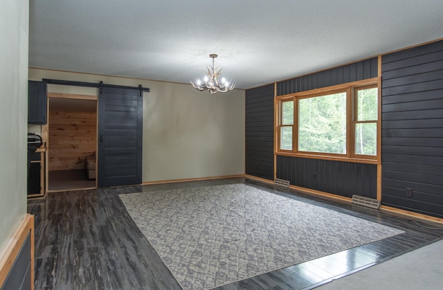 51850 Scenic Hwy Unit 7, Bigfork, MN 56628 - spare room with a barn door, wood finished floors, a chandelier, wooden walls, and baseboards