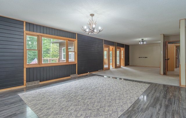 51850 Scenic Hwy Unit 7, Bigfork, MN 56628 - unfurnished room featuring wood finished floors, a chandelier, baseboards, a textured ceiling, and wooden walls