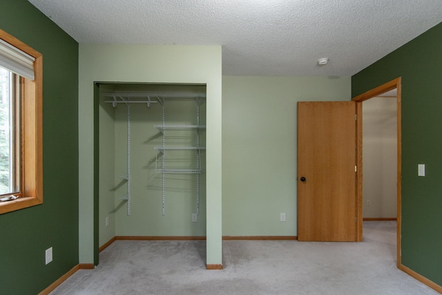 51850 Scenic Hwy Unit 7, Bigfork, MN 56628 - unfurnished bedroom featuring a closet, light carpet, multiple windows, a textured ceiling, and baseboards