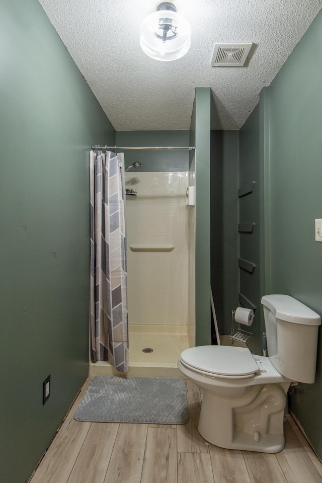 51850 Scenic Hwy Unit 7, Bigfork, MN 56628 - full bath with toilet, a shower stall, a textured ceiling, and wood finished floors