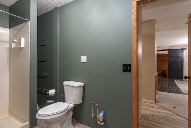 51850 Scenic Hwy Unit 7, Bigfork, MN 56628 - full bathroom featuring toilet, a shower stall, a textured ceiling, and wood finished floors