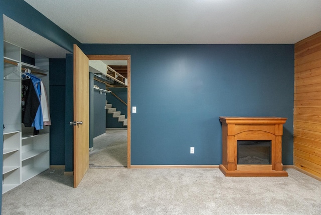 51850 Scenic Hwy Unit 7, Bigfork, MN 56628 - unfurnished living room with carpet flooring, stairway, a glass covered fireplace, baseboards, and wood walls