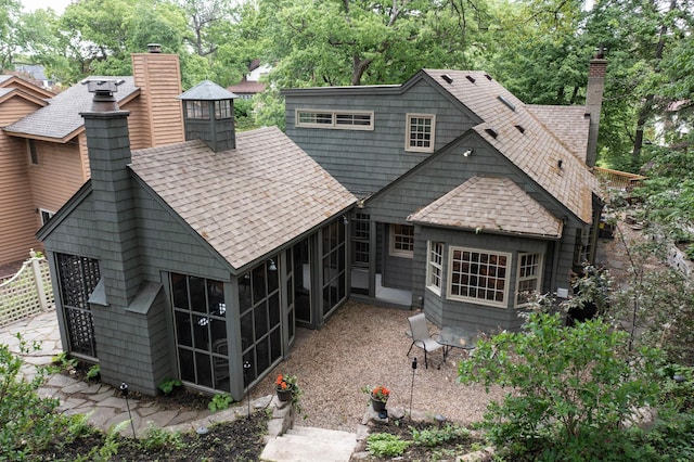 1112 Vincent Ave S, Minneapolis, MN 55405 - back of property featuring a sunroom, a chimney, a shingled roof, and view of wooded area