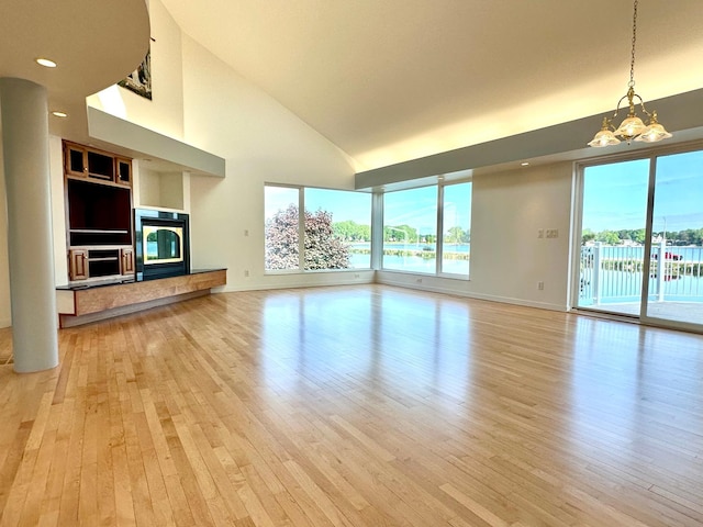 1976 Bay St, Worthington, MN 56187 - unfurnished living room with light wood-type flooring, high vaulted ceiling, baseboards, a chandelier, and a glass covered fireplace