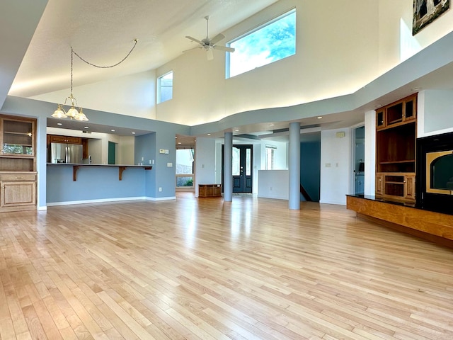 1976 Bay St, Worthington, MN 56187 - unfurnished living room featuring a ceiling fan, light wood-type flooring, a towering ceiling, a chandelier, and baseboards