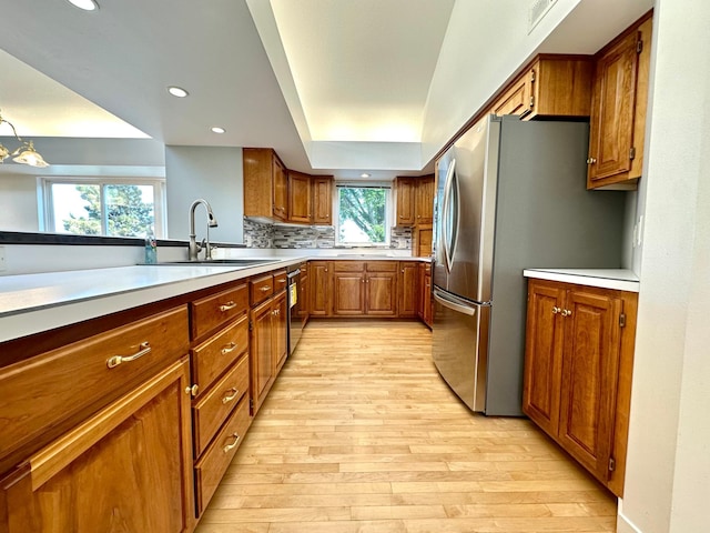 1976 Bay St, Worthington, MN 56187 - kitchen featuring a sink, brown cabinets, light wood-style floors, tasteful backsplash, and recessed lighting