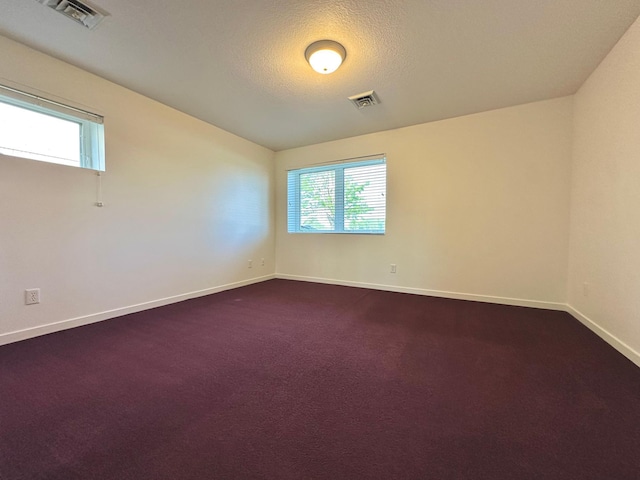 1976 Bay St, Worthington, MN 56187 - unfurnished room with plenty of natural light, baseboards, dark carpet, and a textured ceiling