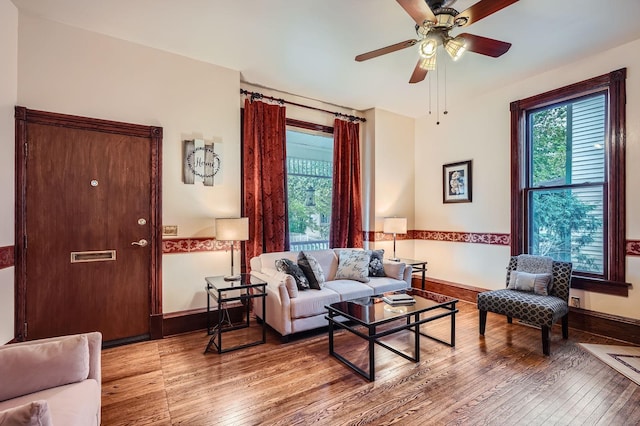 living area with hardwood / wood-style flooring, ceiling fan, and baseboards