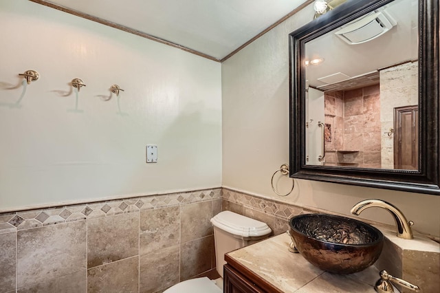 bathroom featuring tile walls, ornamental molding, toilet, a wainscoted wall, and vanity