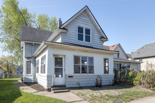 view of front of property featuring entry steps, a chimney, and a shingled roof