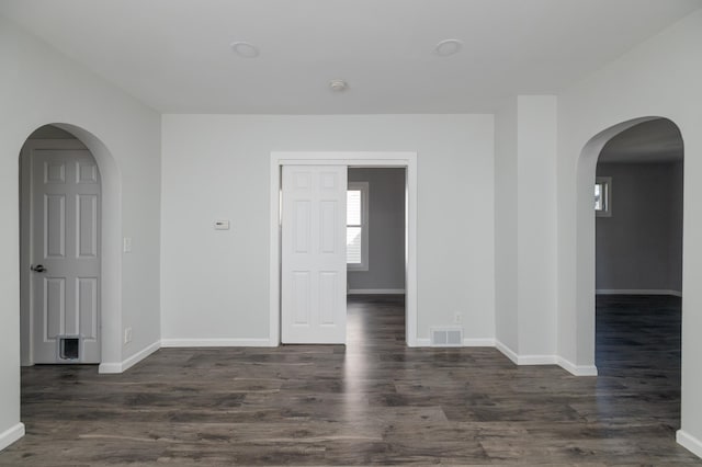 spare room with baseboards and dark wood-type flooring