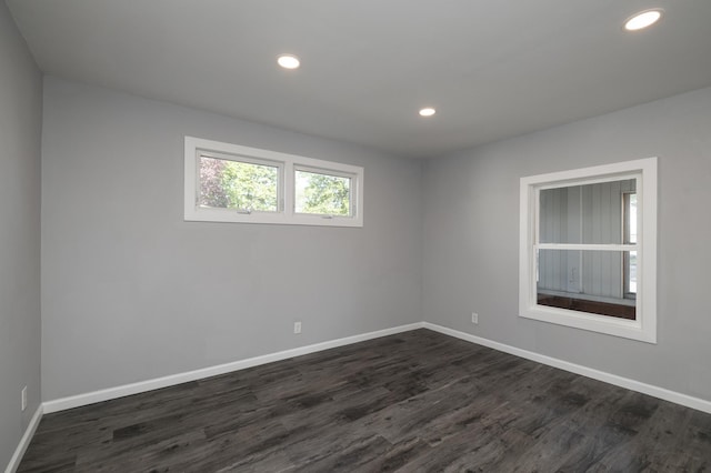 spare room with dark wood-style flooring, baseboards, and recessed lighting