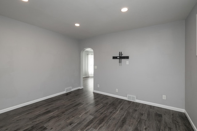 unfurnished room featuring arched walkways, dark wood-style floors, baseboards, and recessed lighting